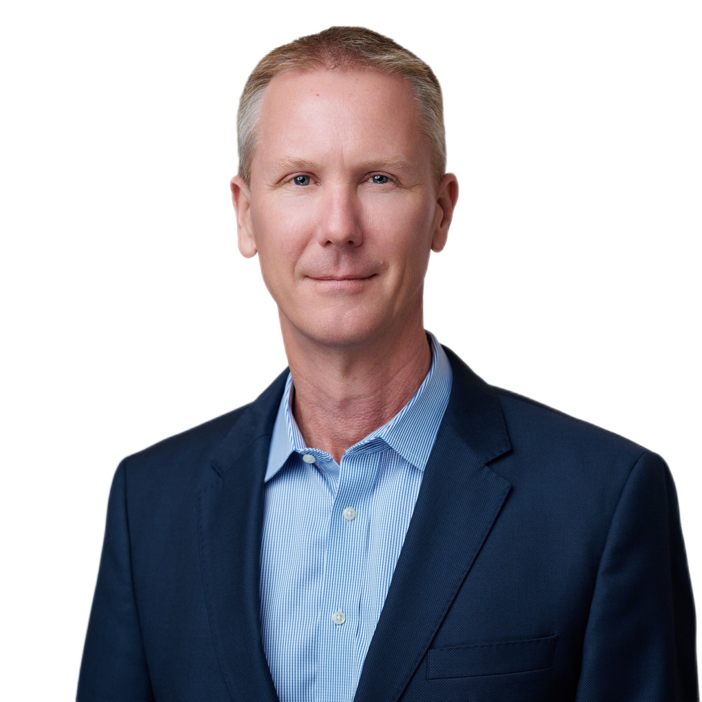 Man with short blond hair wearing a blue suit jacket and light blue collared shirt, posing against a plain white background.