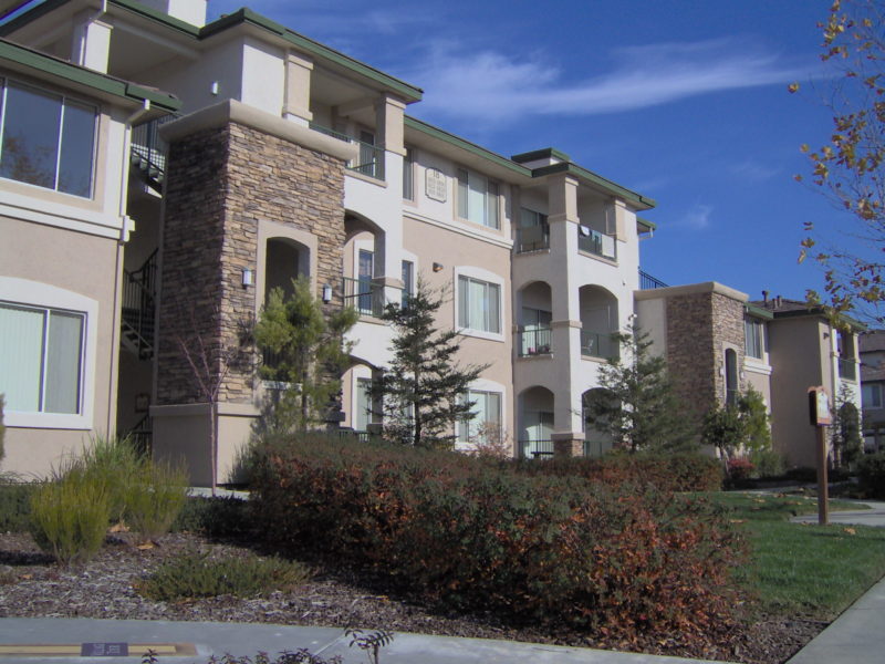 Cream and tan apartment buildings with green trimming and brown stonework on the columns