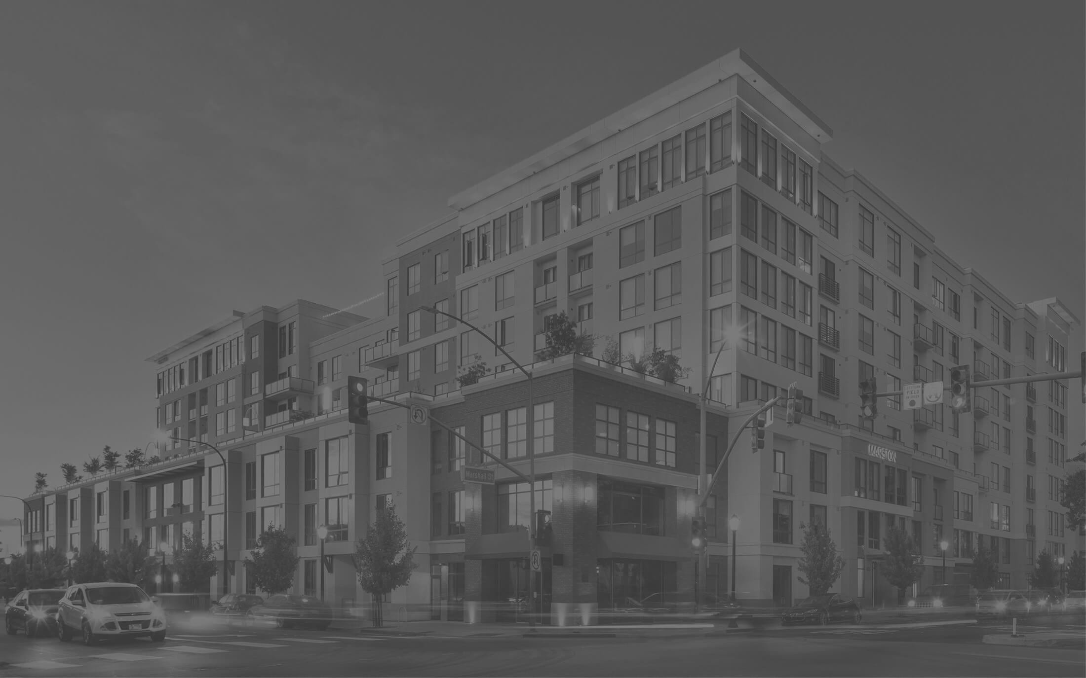 Street view of large apartment buildings with a rooftop patio in black and white