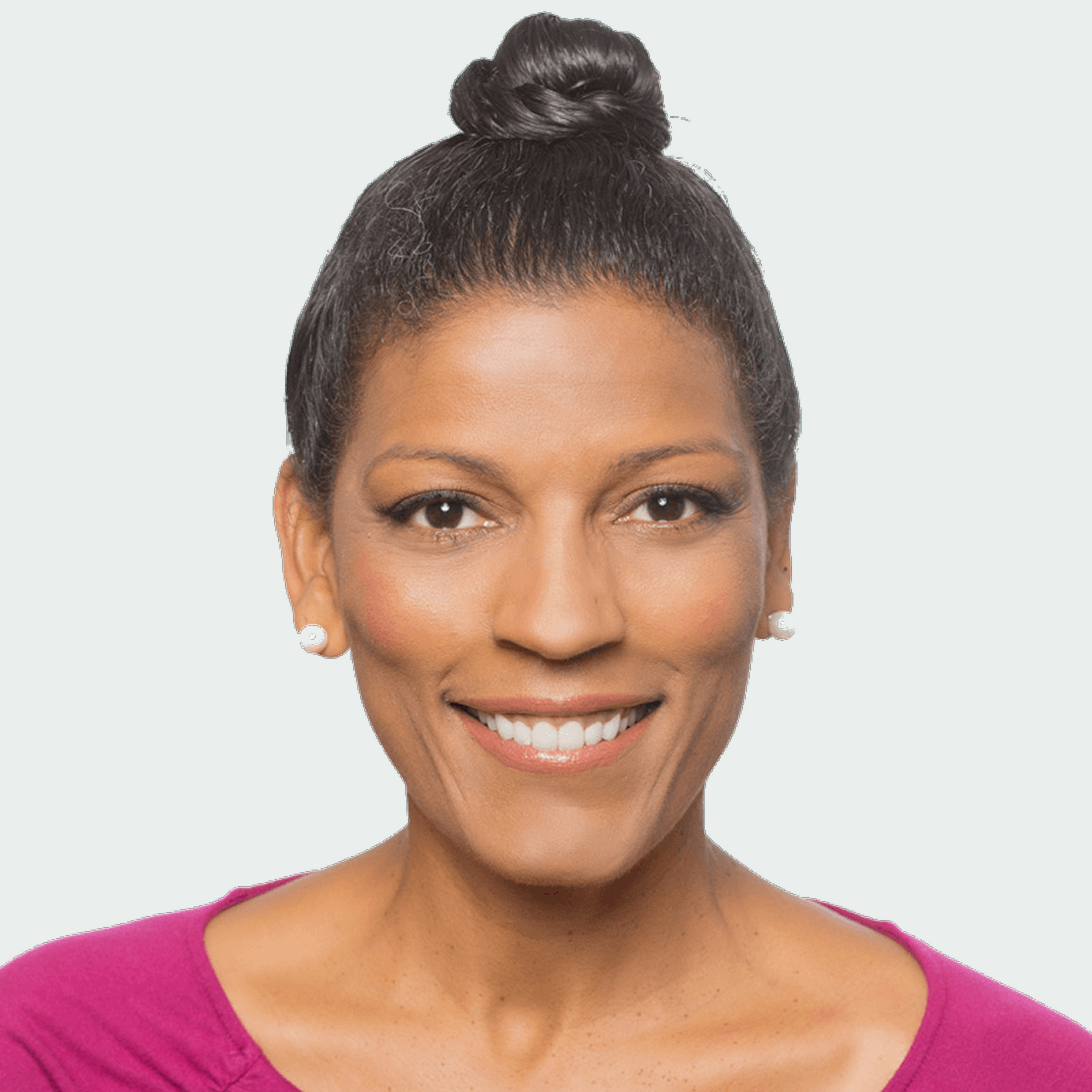 A woman with dark hair in a top bun, wearing pearl earrings and a magenta top, smiles at the camera against a plain light background.