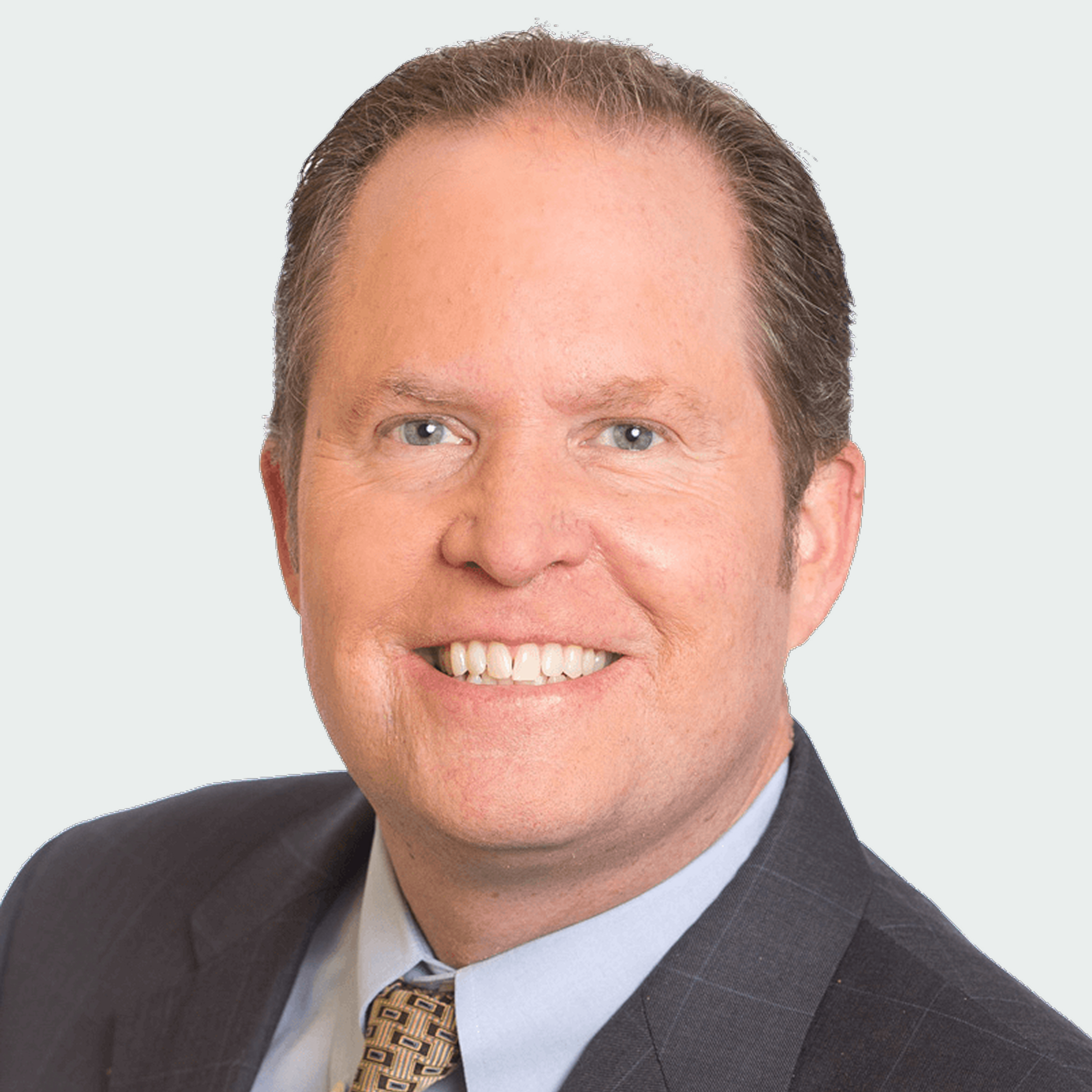 Smiling middle-aged man in a suit and tie against a plain light background.