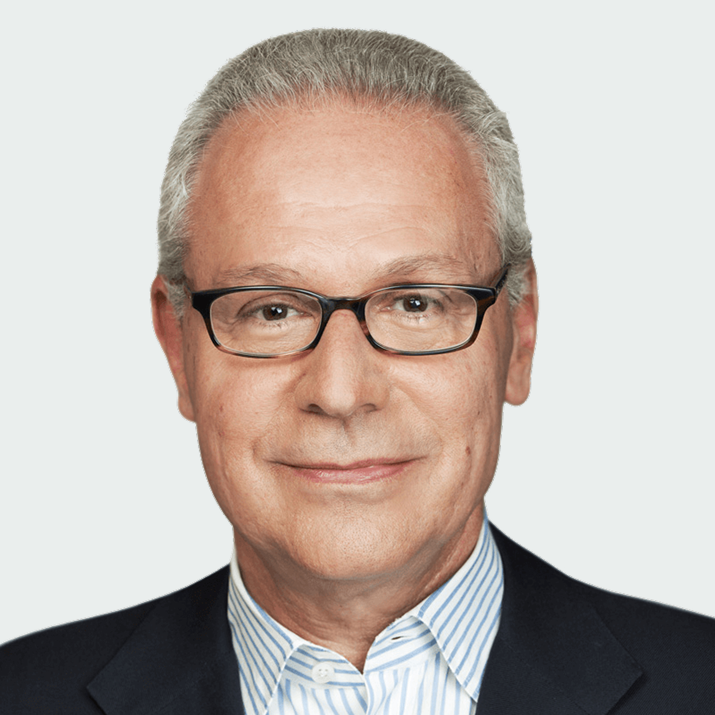 A middle-aged man with short gray hair, glasses, and a suit jacket over a striped shirt, facing the camera and smiling slightly.