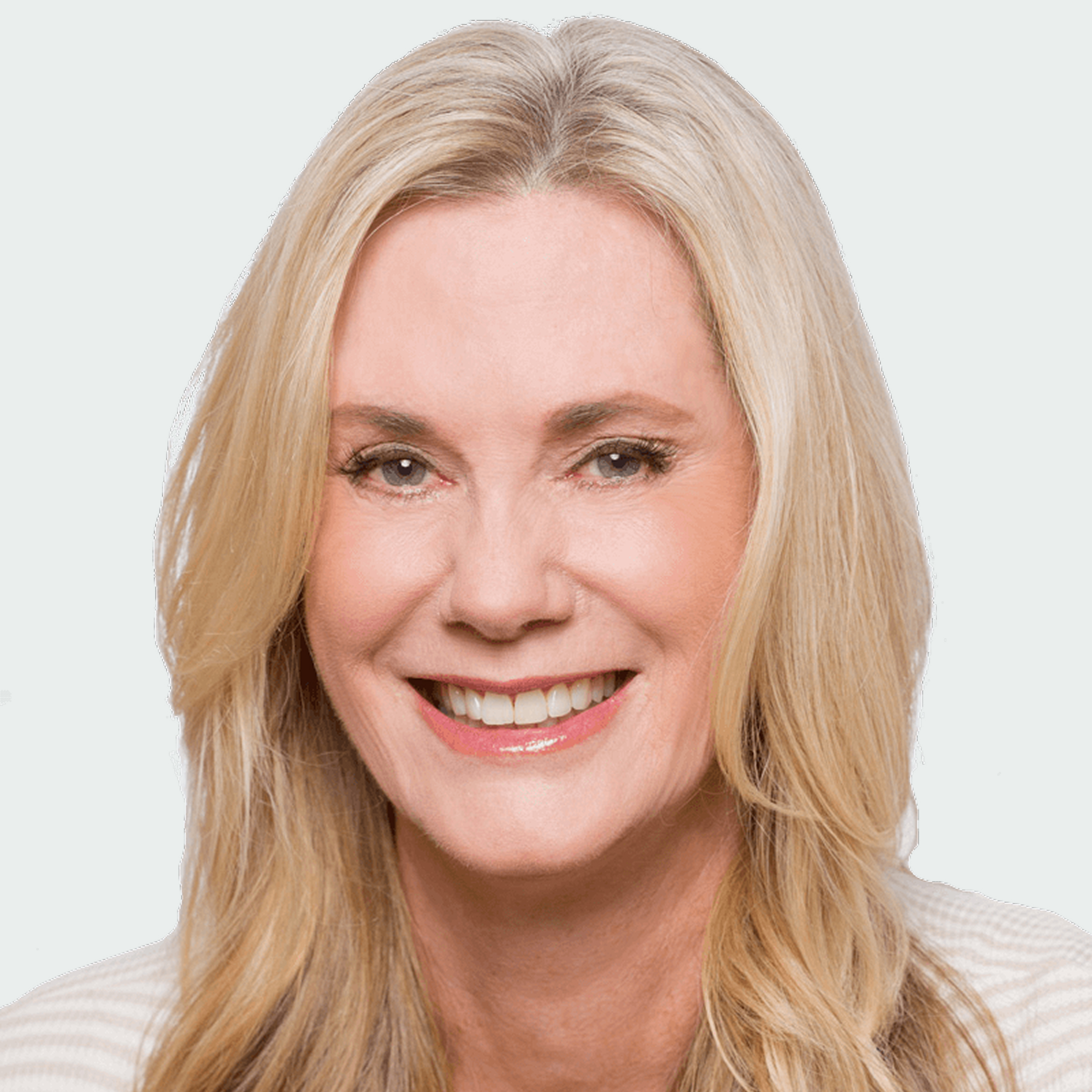 Smiling woman with long blonde hair, wearing a light-colored top, facing forward against a plain light background.