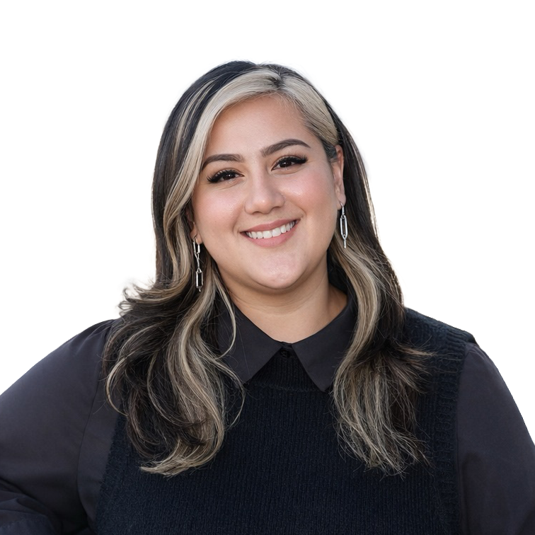 Woman with long, wavy, dark hair with blonde highlights, wearing a black collared shirt and vest, smiling at the camera against a plain light background.